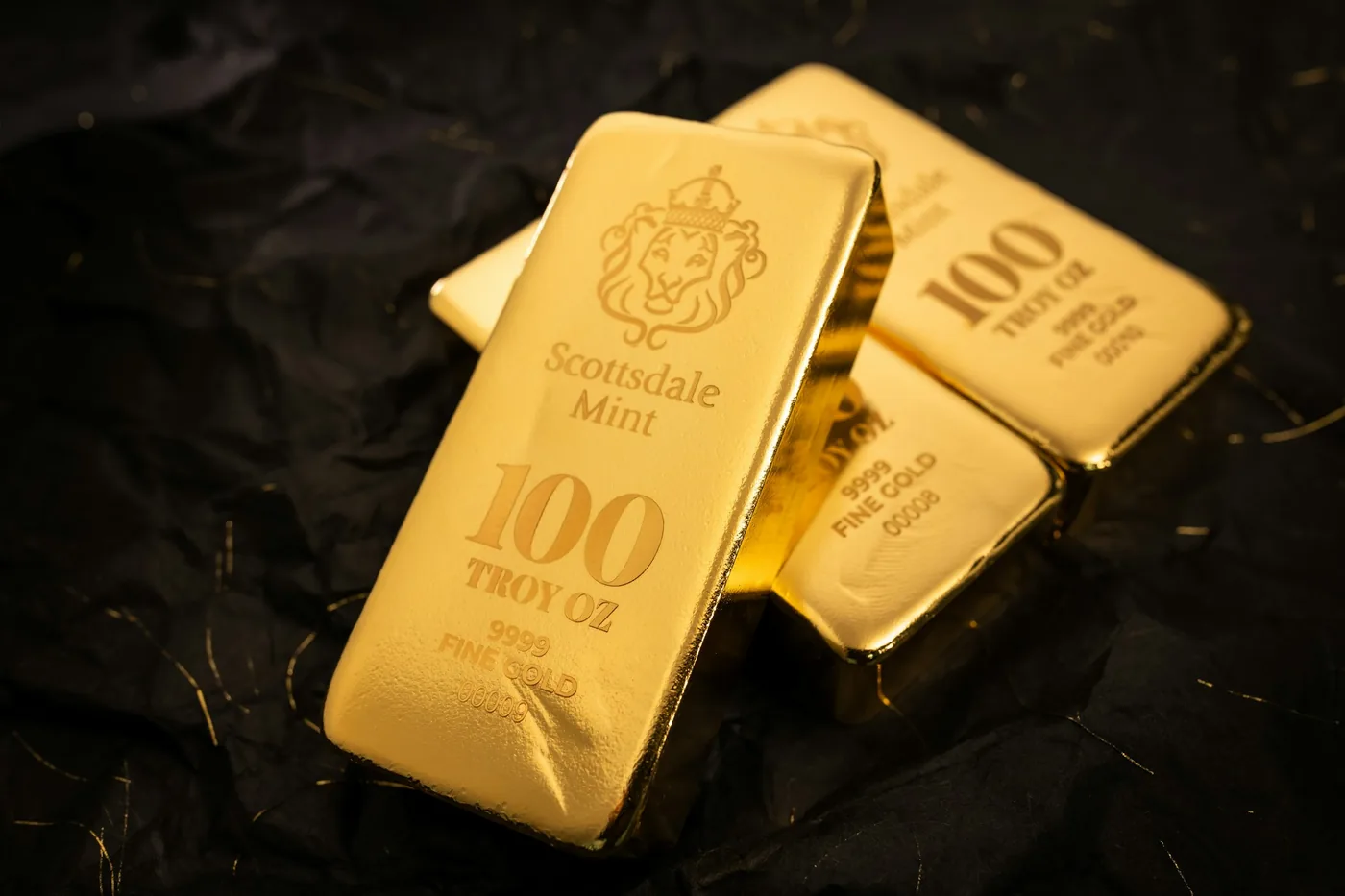 Minted 100 troy ounce gold bars on dark cloth