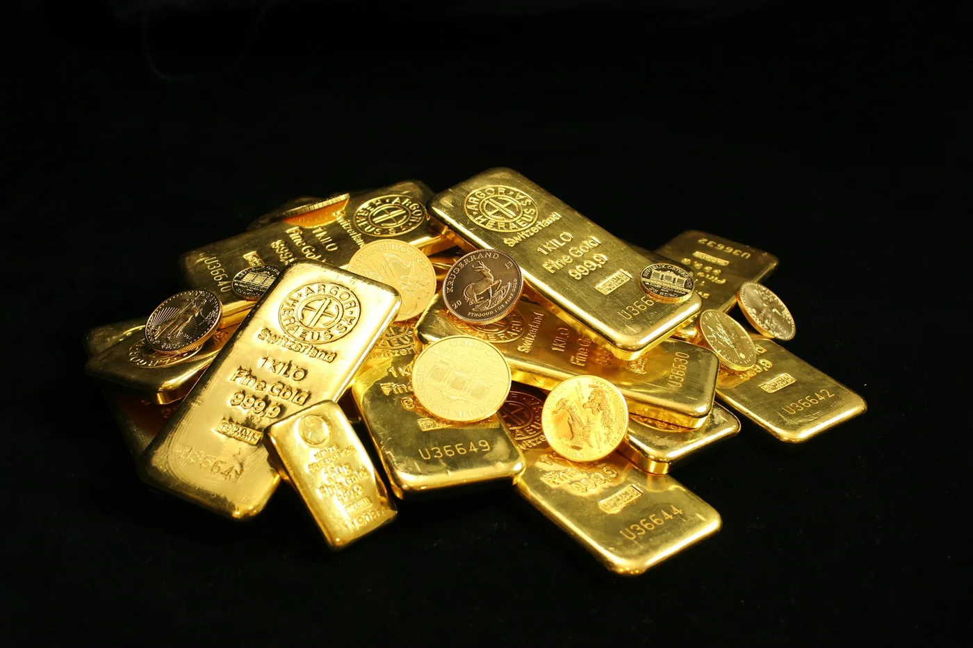 A pile of gold bars and coins on a black surface